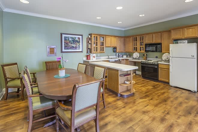 A modern kitchen and dining area with wooden cabinets, an island counter, and a large dining table.