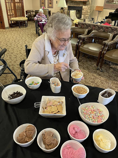 An elderly woman enjoying a variety of ice cream flavors at a social gathering.