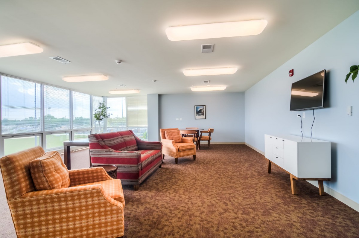 Spacious living room with comfortable seating arrangements and large windows.