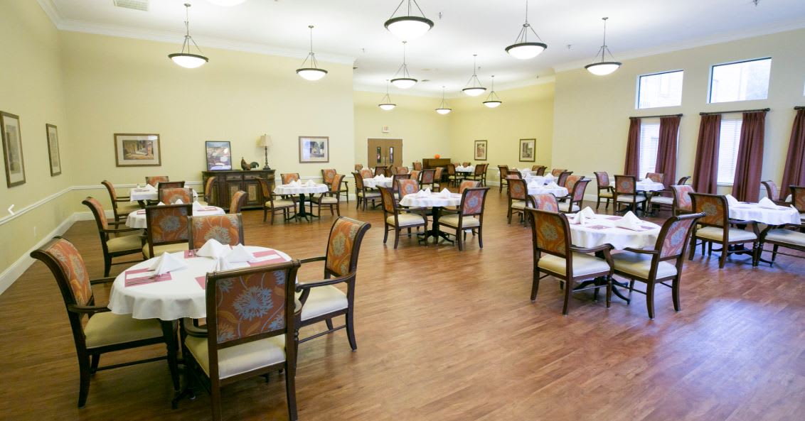 An elegant and empty dining room with neatly set tables and chairs.