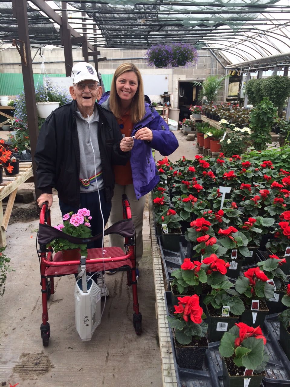 Two people enjoying a visit to a greenhouse, browsing colorful flowers.
