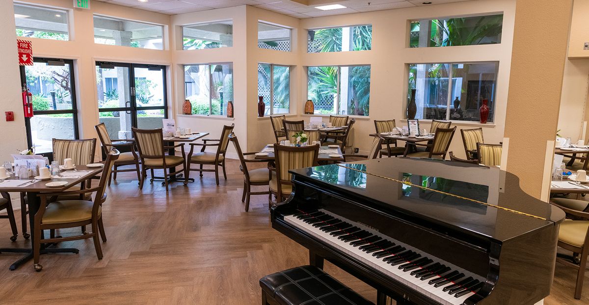 A cozy dining area featuring a piano and elegantly set tables.