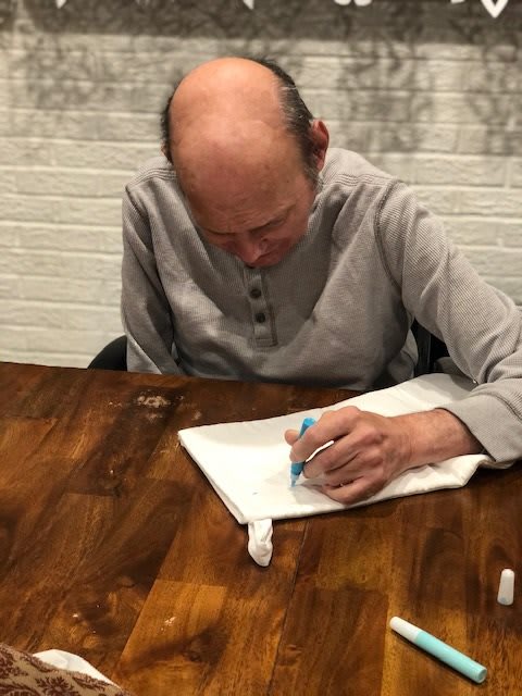 A person is focused on writing in a notebook at a wooden table.