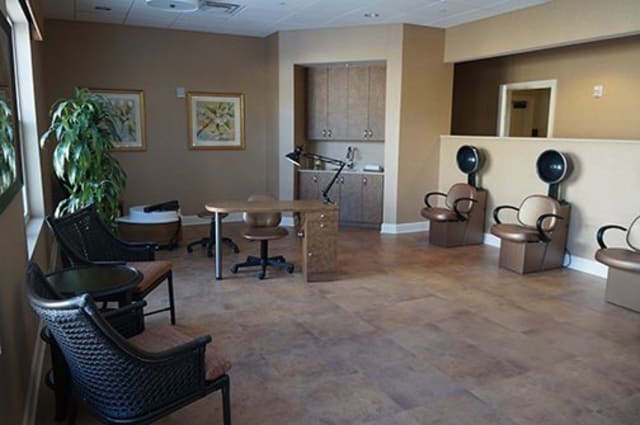 A cozy salon waiting area with chairs, small tables, and hair dryers.