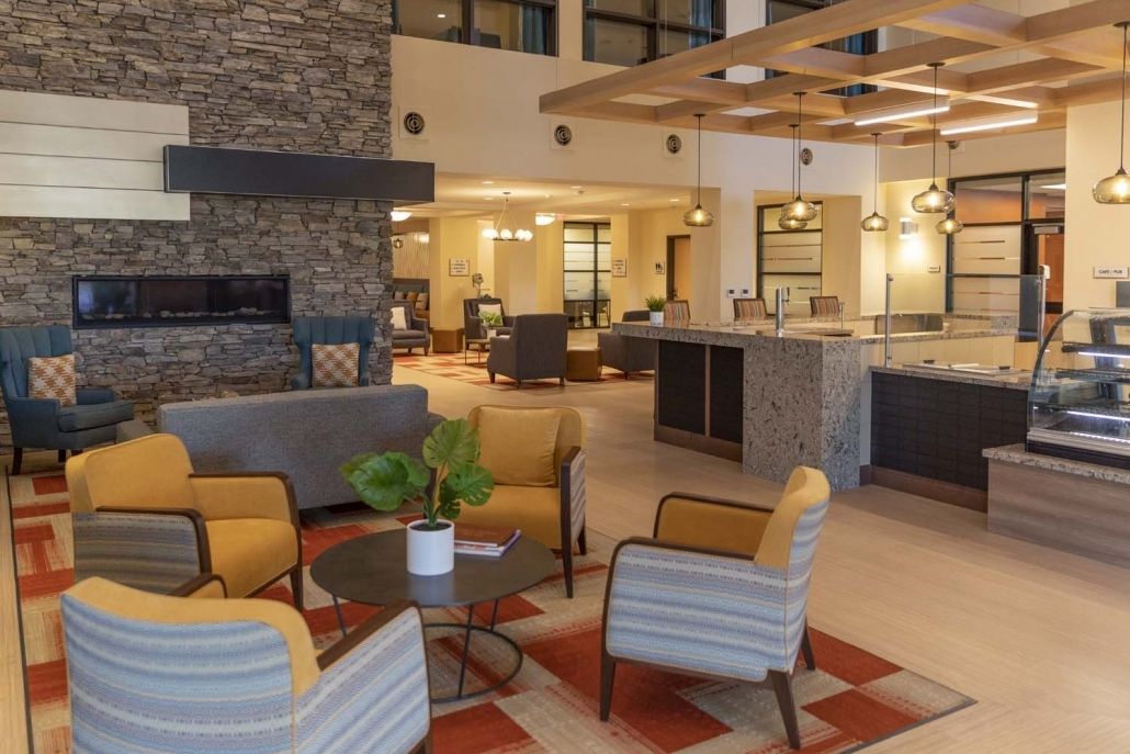 A modern hotel lobby featuring comfortable seating and a stone fireplace.