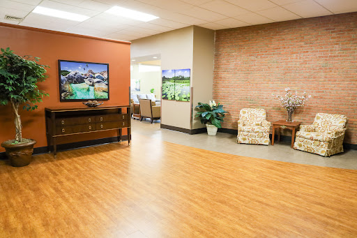 A well-lit lobby featuring comfortable seating, vibrant wall colors, and decorative plants.