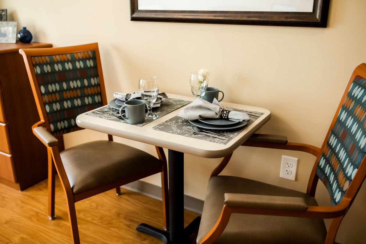 A cozy dining table set for two with cups and plates.