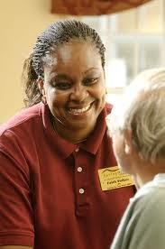 A caregiver smiling while interacting with an elderly person.