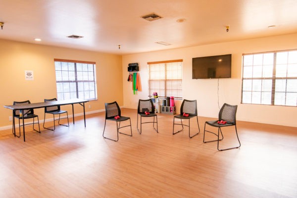 An empty meeting room with chairs arranged in a circle and a television on the wall.