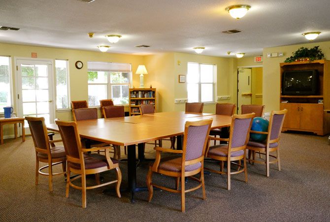 A spacious conference room with a large wooden meeting table surrounded by chairs under warm lighting.