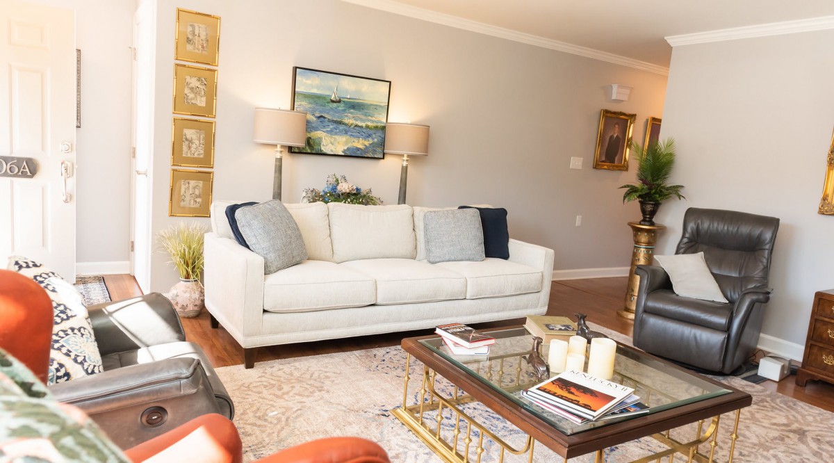 A cozy living room with a white sofa, decorative pillows, and a glass coffee table.