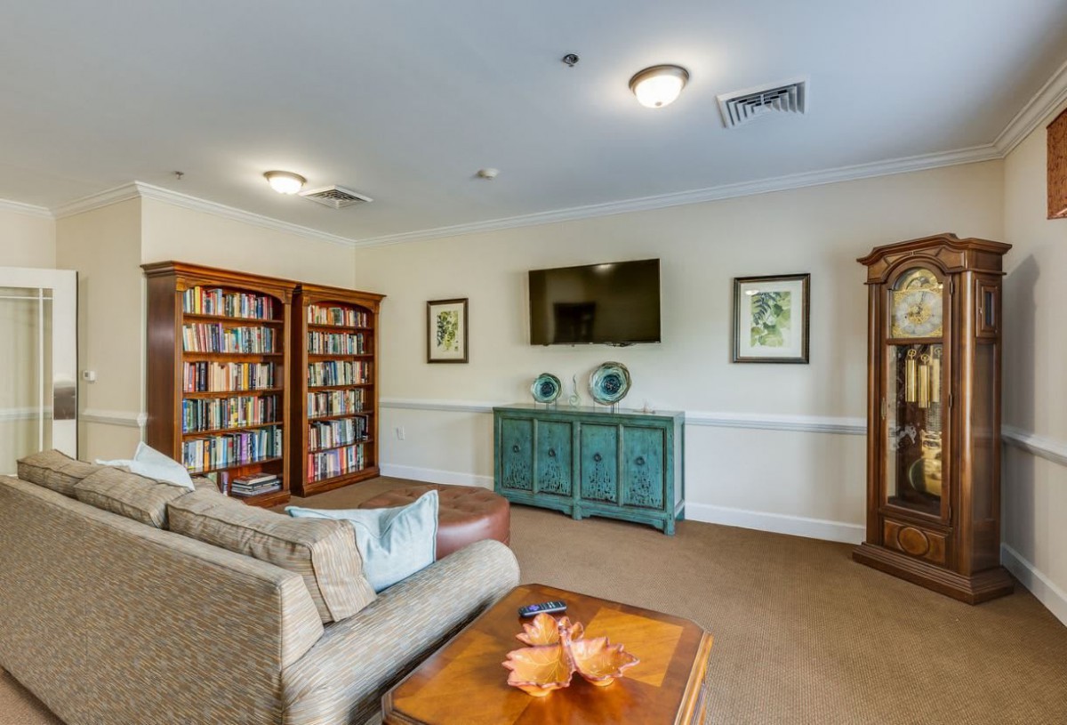 A cozy reading room with bookshelves, comfortable seating, and a television.