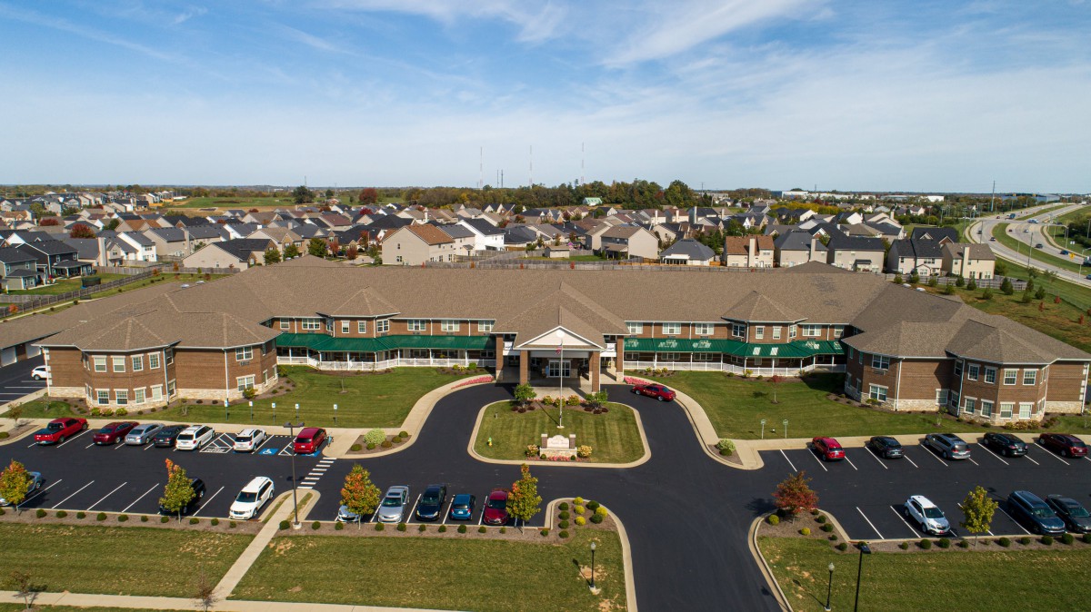 Aerial view of a large building with surrounding residential area and parking lot.