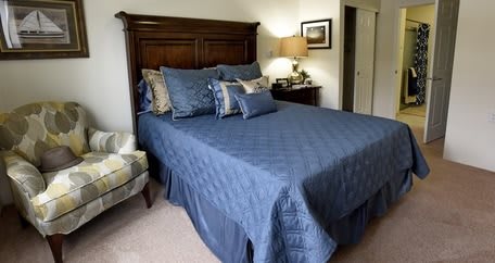 A neatly arranged bedroom with a blue quilt and matching pillows.