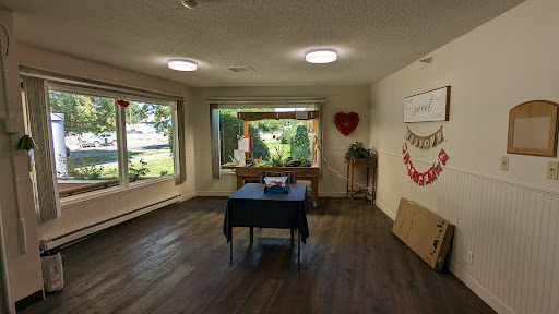 A spacious and well-lit indoor room featuring a black table, large windows, and decorative elements.