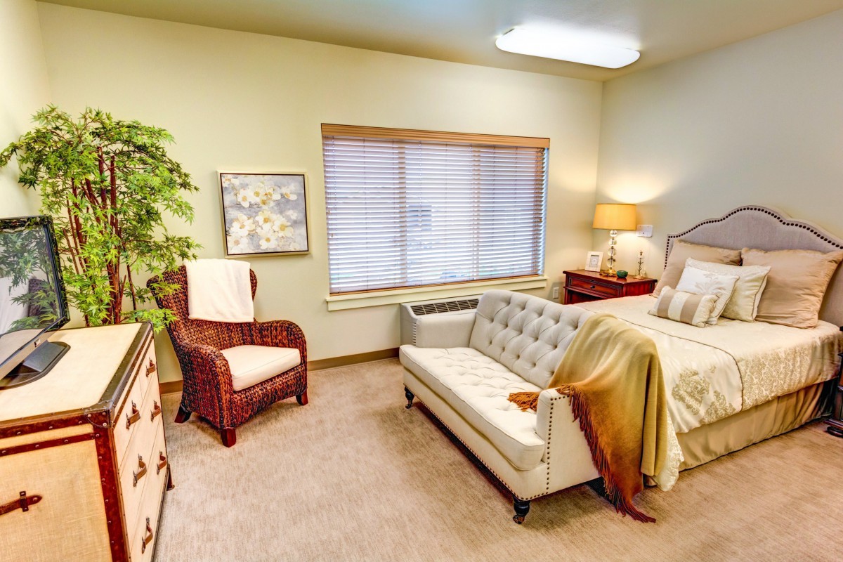 A cozy bedroom with a sofa and a comfortable bed beside a window.