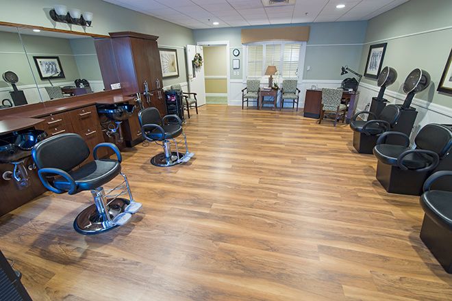 Interior view of a beauty salon with styling chairs and mirrors on a wooden floor.