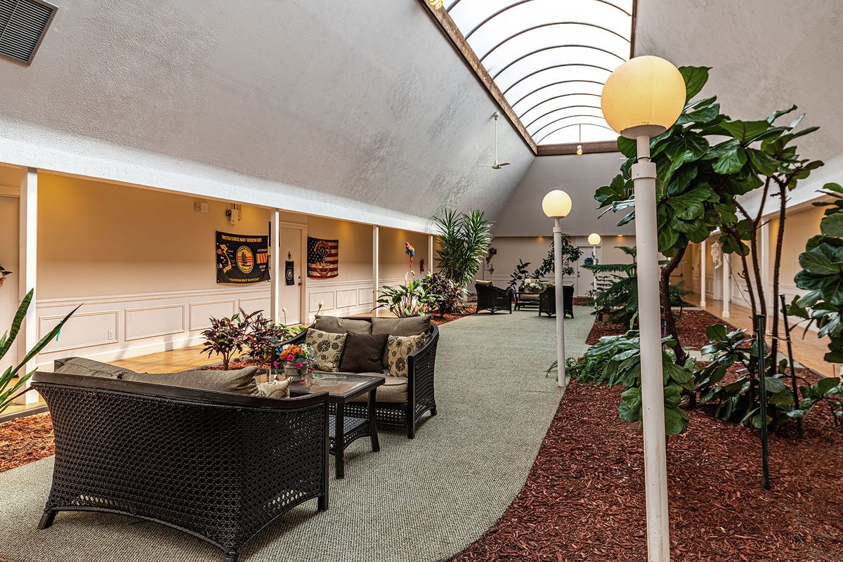 A spacious lobby featuring comfortable seating, skylight, and decorative plants.