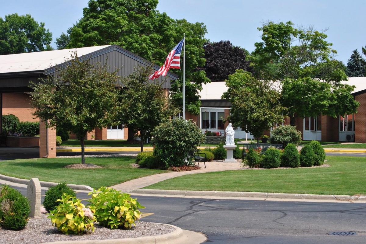 A building with an American flag, surrounded by a well-maintained garden and pathway.
