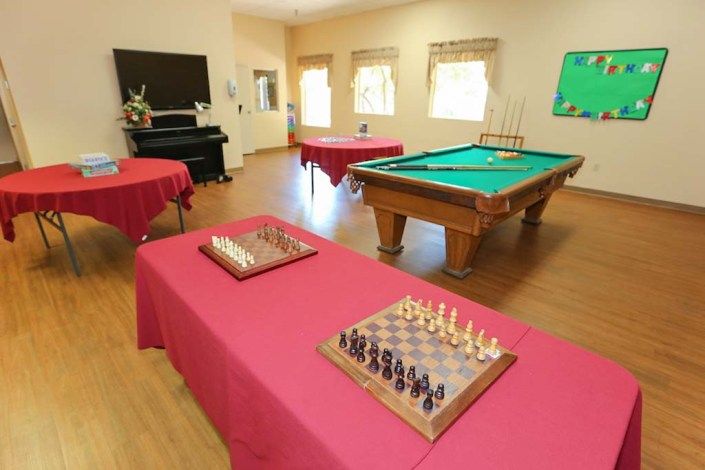 A recreation room featuring chess boards, a billiards table, and a piano.