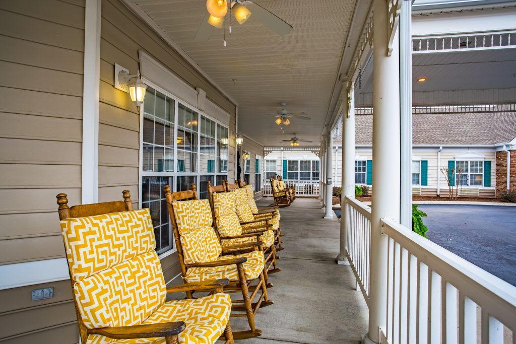 A cozy porch featuring several rocking chairs with patterned cushions, inviting relaxation.