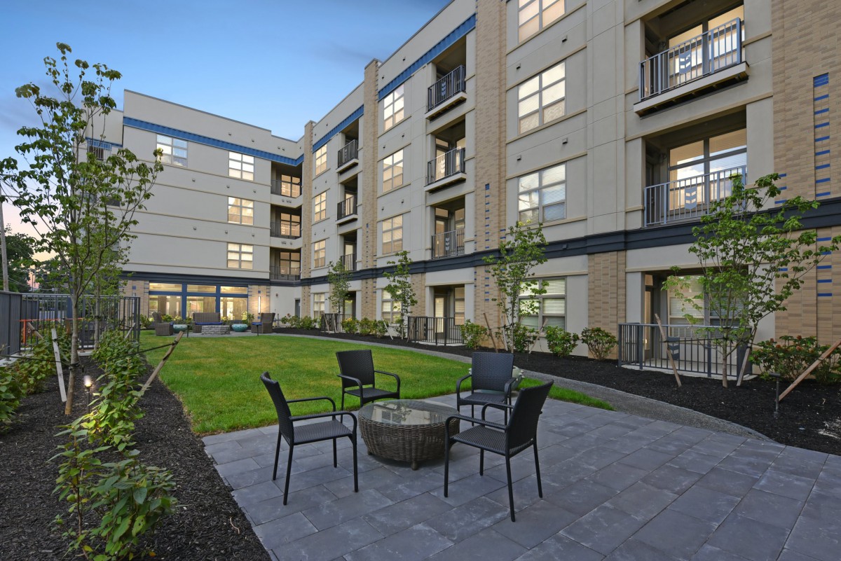 A modern apartment building with a central courtyard featuring outdoor seating.