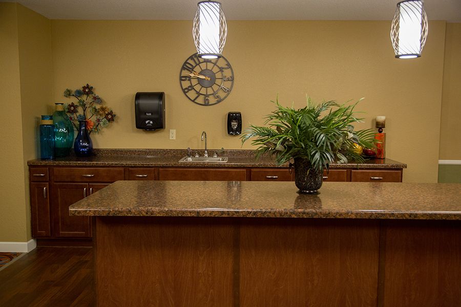 A contemporary kitchen with a central island, featuring a potted plant and a clock on the wall.