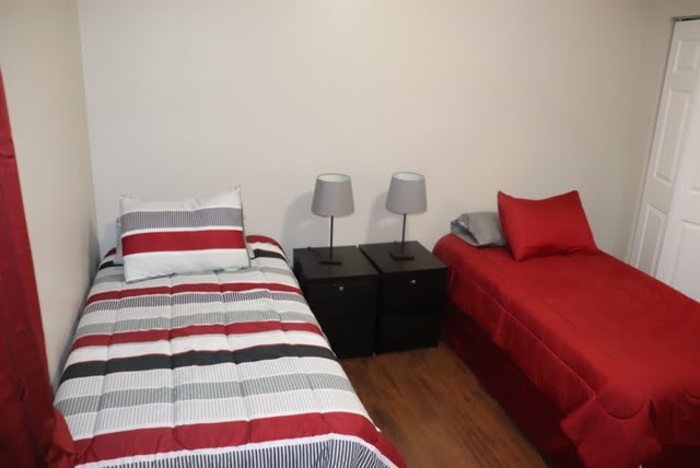 A cozy bedroom with two beds, each with colorful bedding and a nightstand with lamps in between.