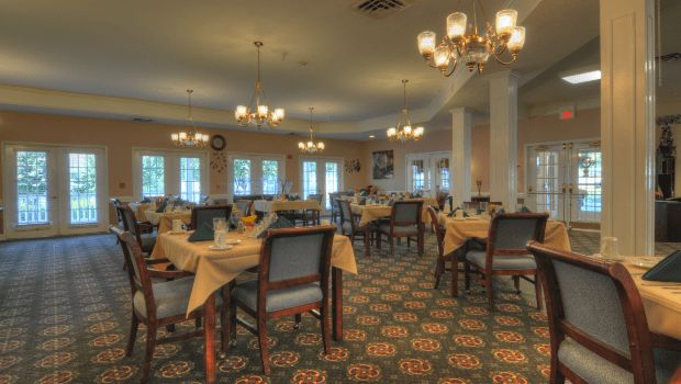 A well-decorated dining room with tables set for service, featuring chandeliers and elegant decor.
