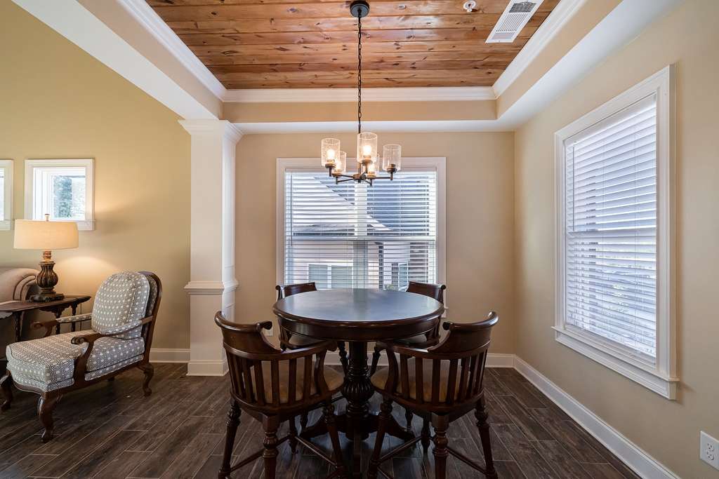 A cozy dining room with a round table and chairs, featuring a chandelier and tray ceiling.