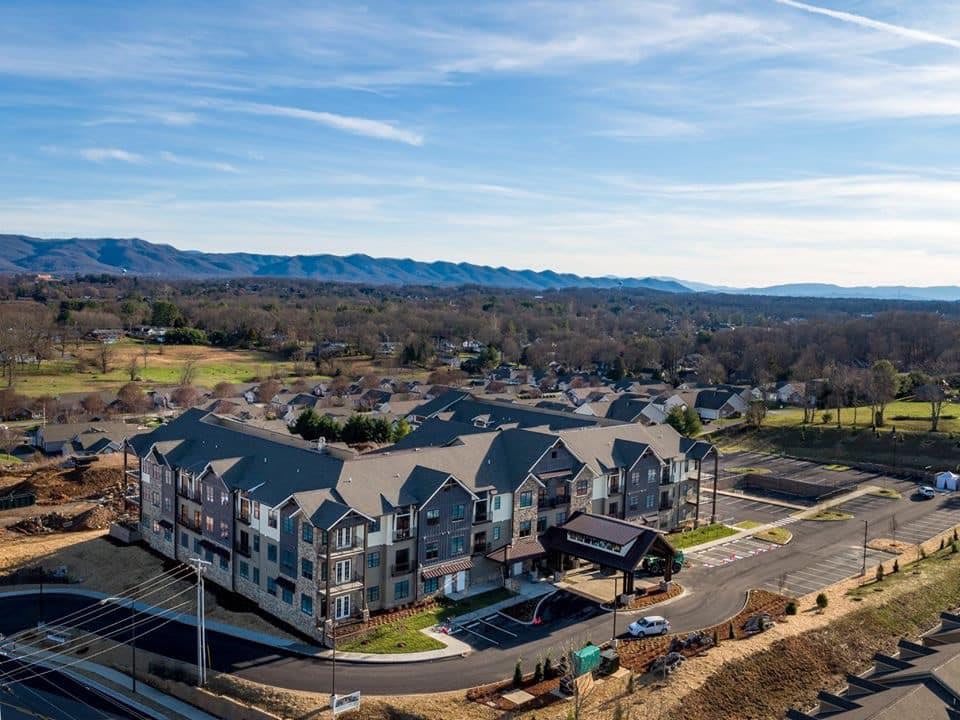 Aerial view of a residential apartment complex surrounded by roads and scenic mountains.