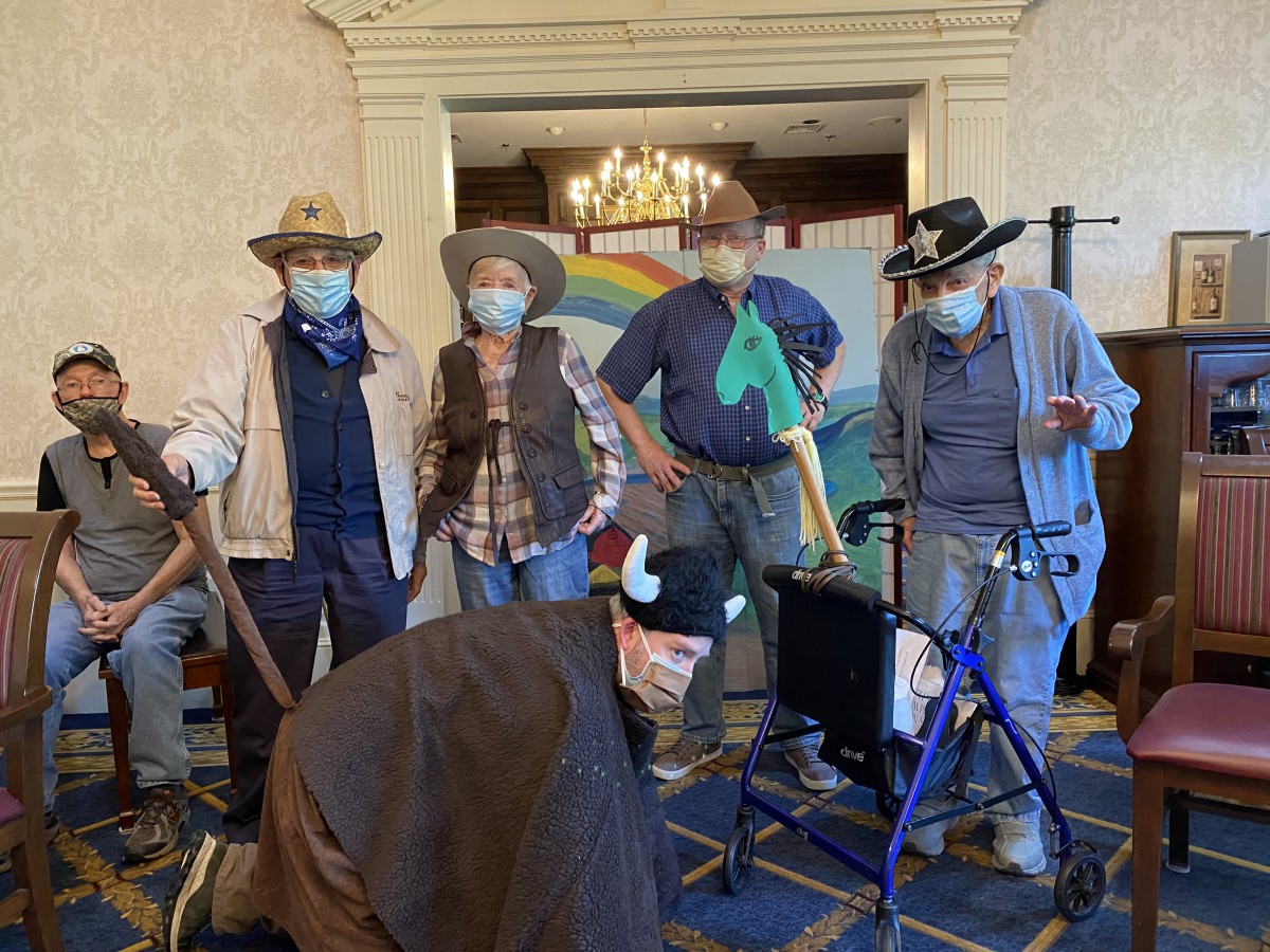 A group of people dressed in cowboy costumes, wearing masks and standing indoors.