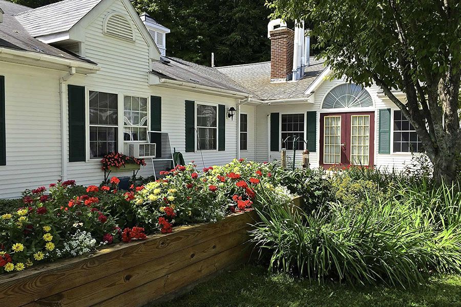 A charming house with a vibrant flower garden in the front yard.