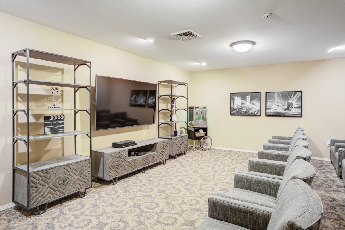 A modern home theater with comfortable seating, a large TV, and stylish shelving.