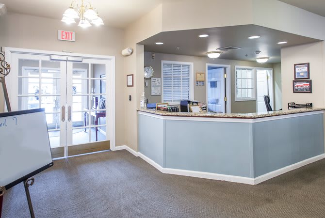 A brightly lit office reception area with a desk and large windows.