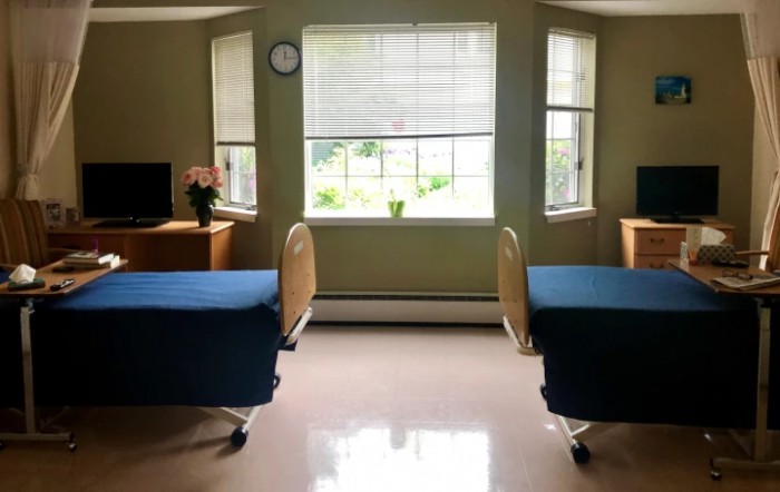 A well-lit hospital room with two beds and a large window.