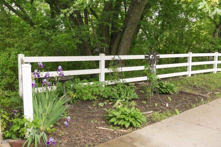 A serene garden scene with a white fence and blooming flowers.