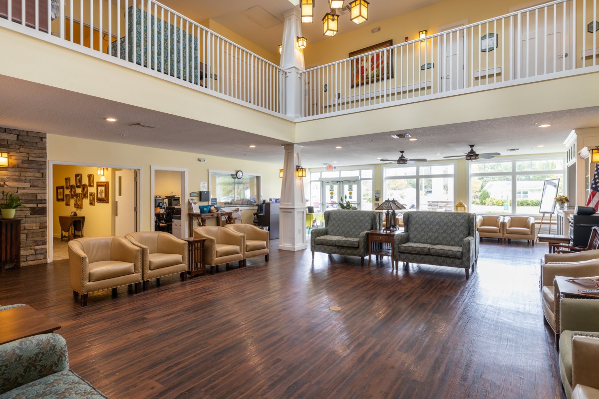 A spacious and modern lobby with wooden floors, featuring comfortable seating areas.