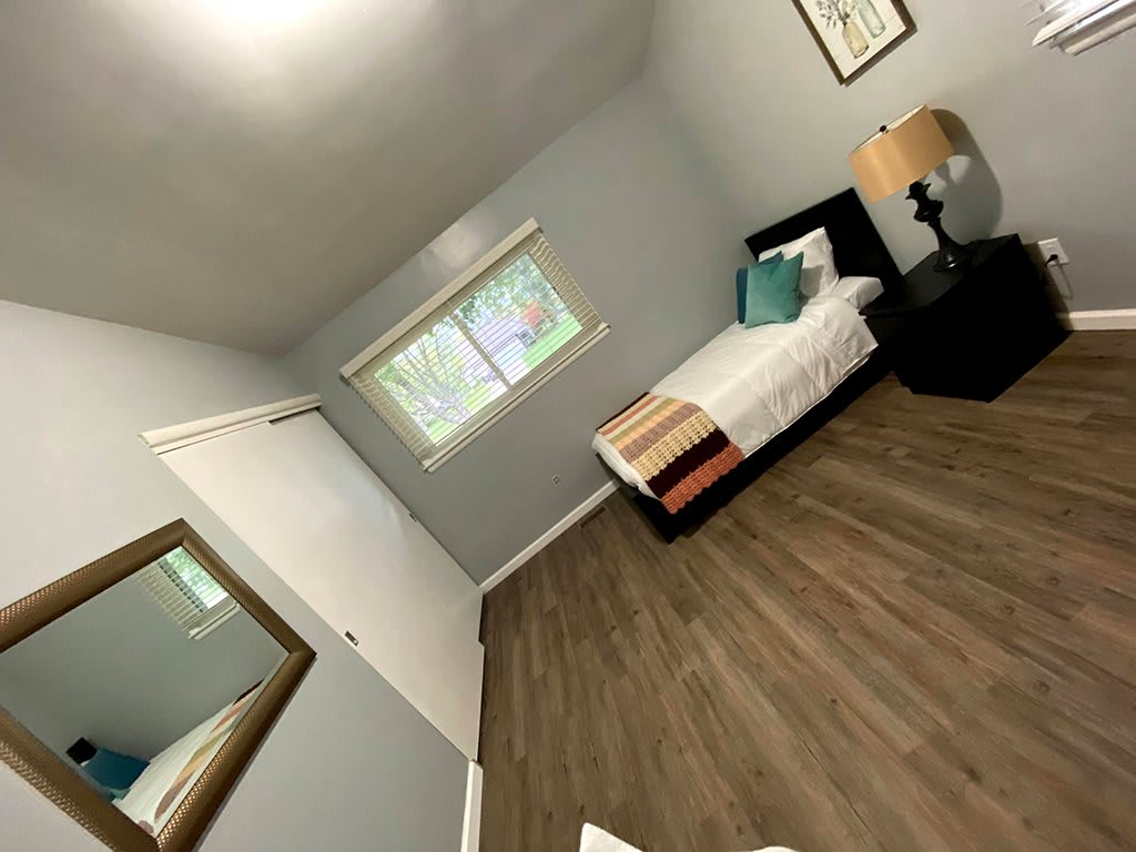 A minimalist bedroom with a single bed and hardwood flooring.
