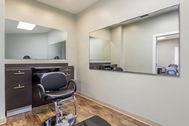 A minimalist hair salon interior featuring a styling chair and large mirrors.