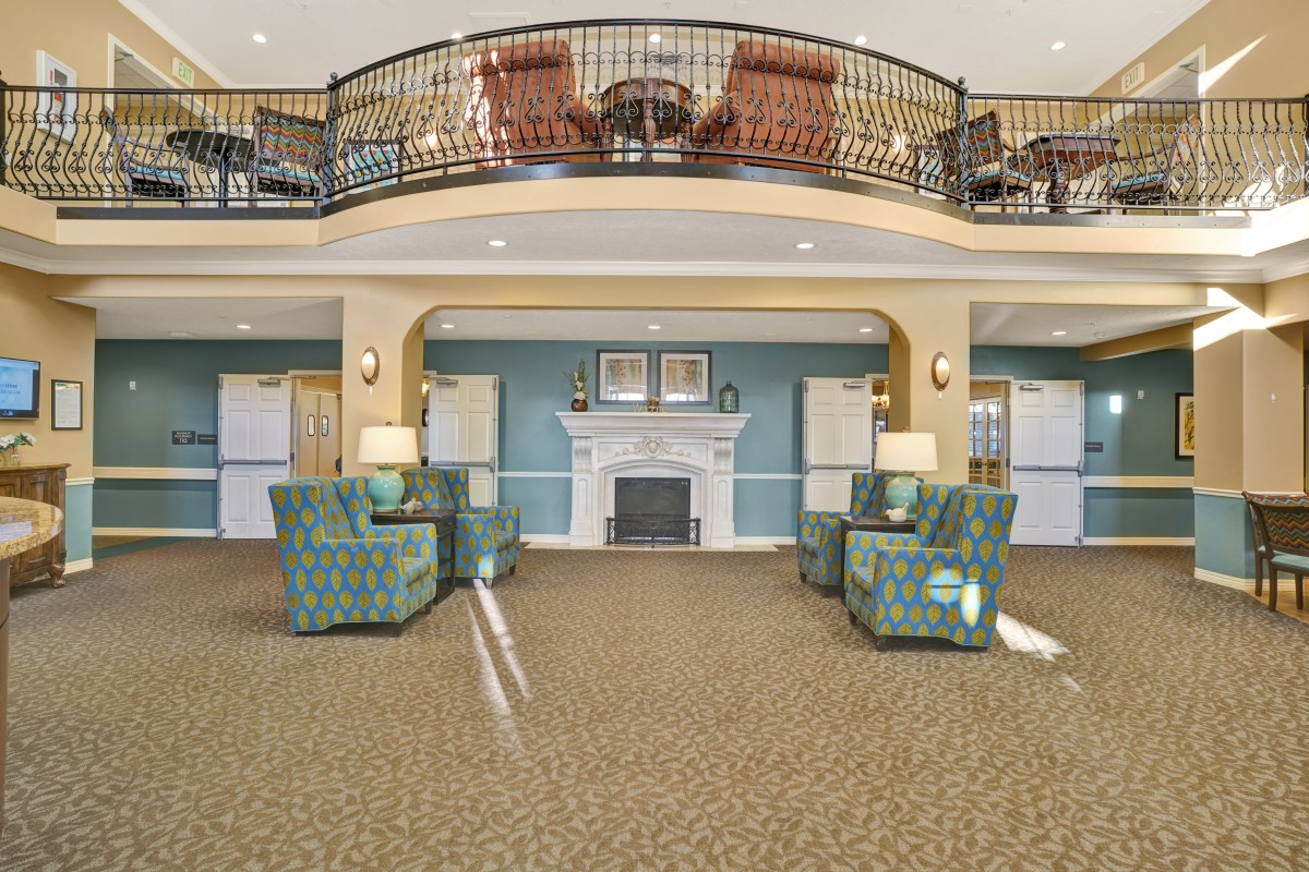 A spacious and elegantly designed lobby with comfortable seating, a central fireplace, and an overlooking balcony.