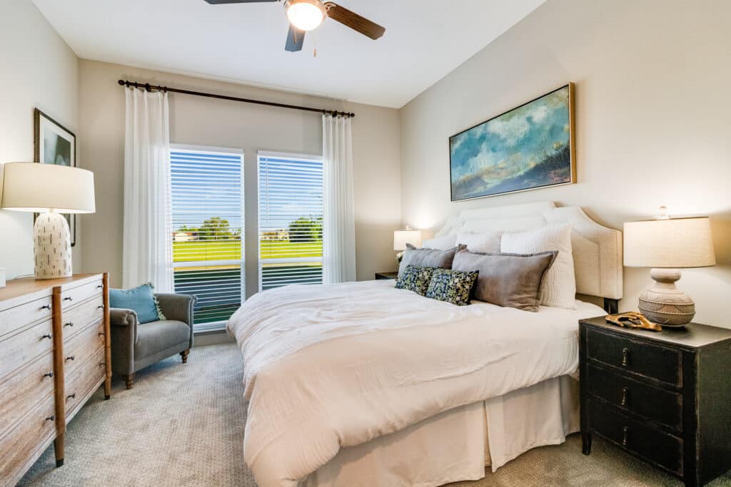 A cozy bedroom with a large bed, natural light from windows, and tasteful decor.