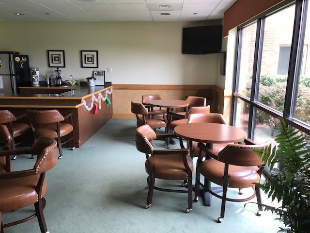A small lounge area with tables, chairs, and large windows.