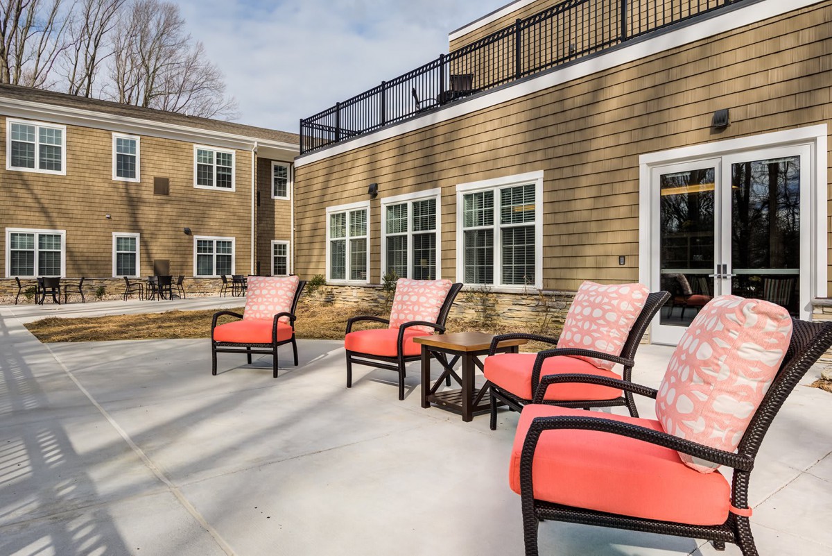 A sunny outdoor patio with comfortable chairs and a view of the building.