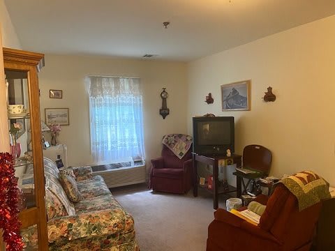 A cozy living room with a sofa and armchair, featuring a TV and various decorations.
