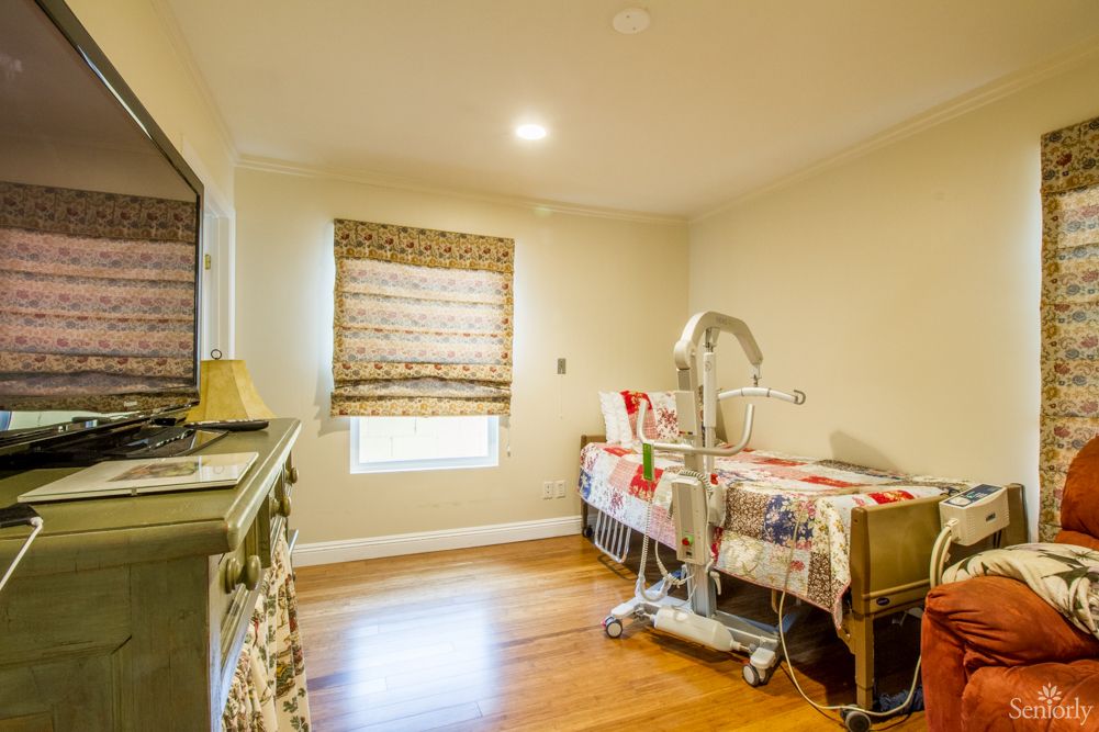 A cozy room with a wooden floor, a decorated table, and a patterned window shade.