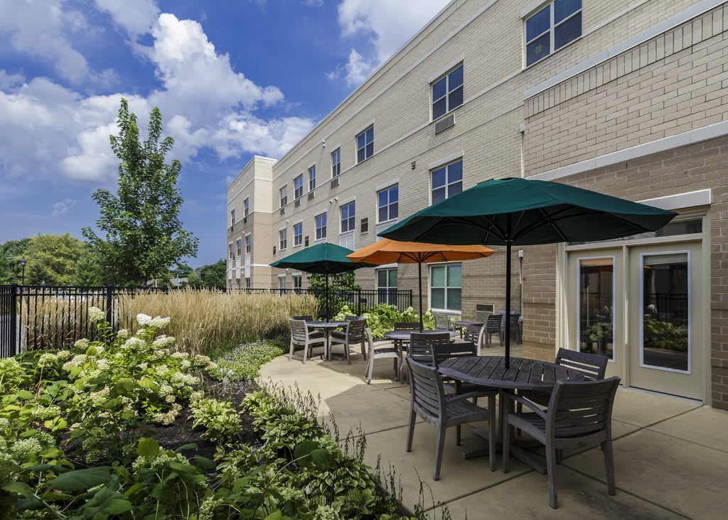 A scenic patio area outside an apartment complex with outdoor seating and colorful umbrellas.