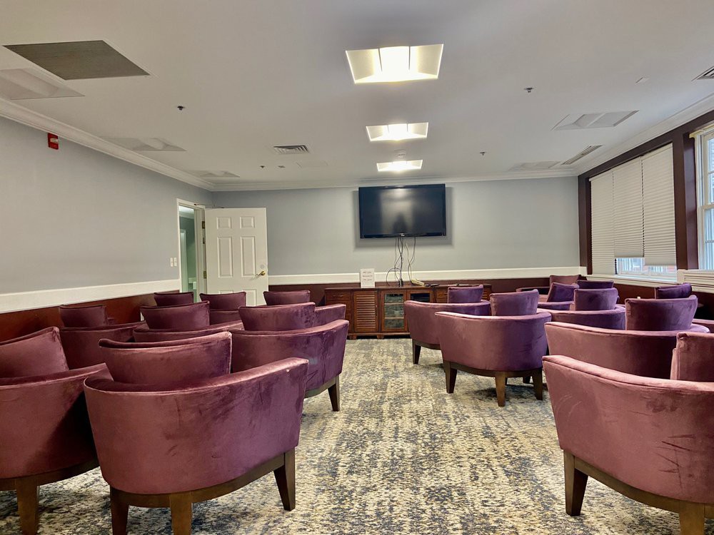 A conference room with purple chairs arranged facing a television screen.
