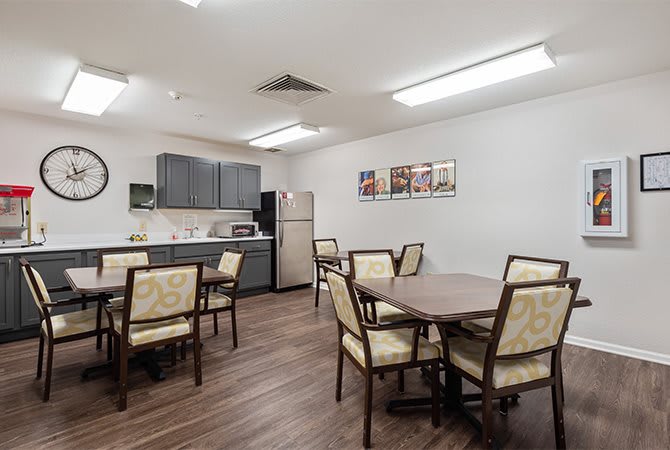 A modern dining area with multiple tables and chairs adjacent to a kitchen space.