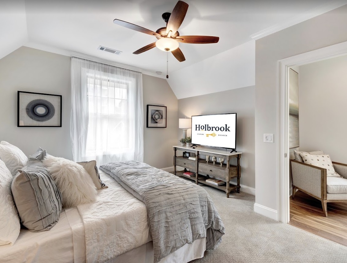 A cozy bedroom featuring a comfortable bed, ceiling fan, and a television with neutral tones throughout the interior design.